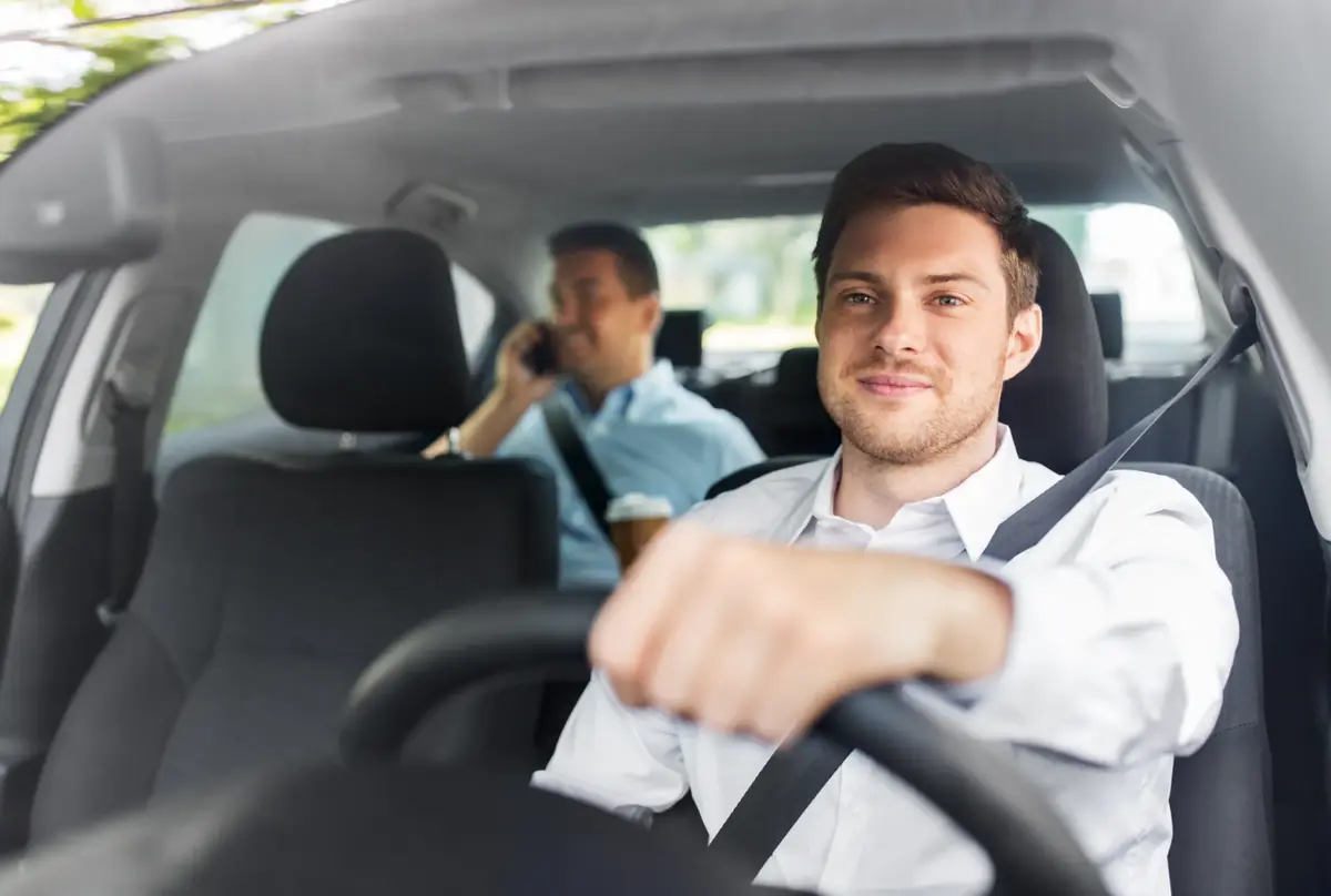 Belted driver at the wheel of a vehicle with a belted passenger seated behind
